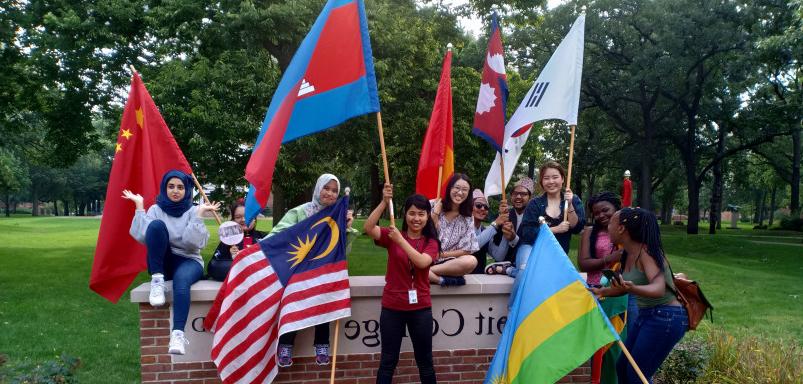 毕业典礼结束后，国际学生在MG官方电子平台的标志前挥舞着他们的旗帜...